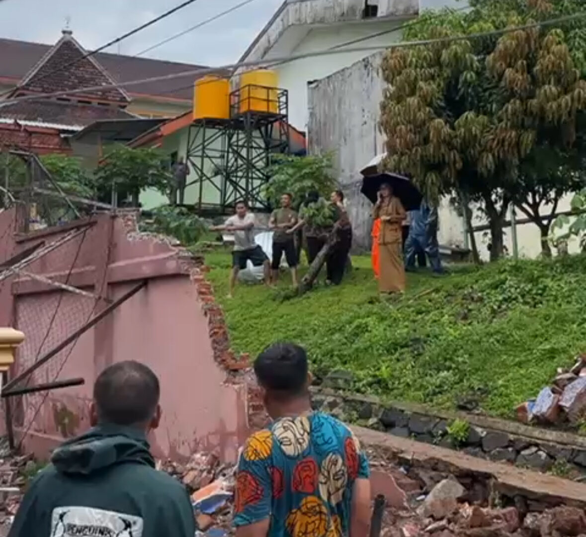 Petugas BPBD Dan Warga Merobohkan Bagian Tembok Miring Untuk Cegah Insiden Susulan