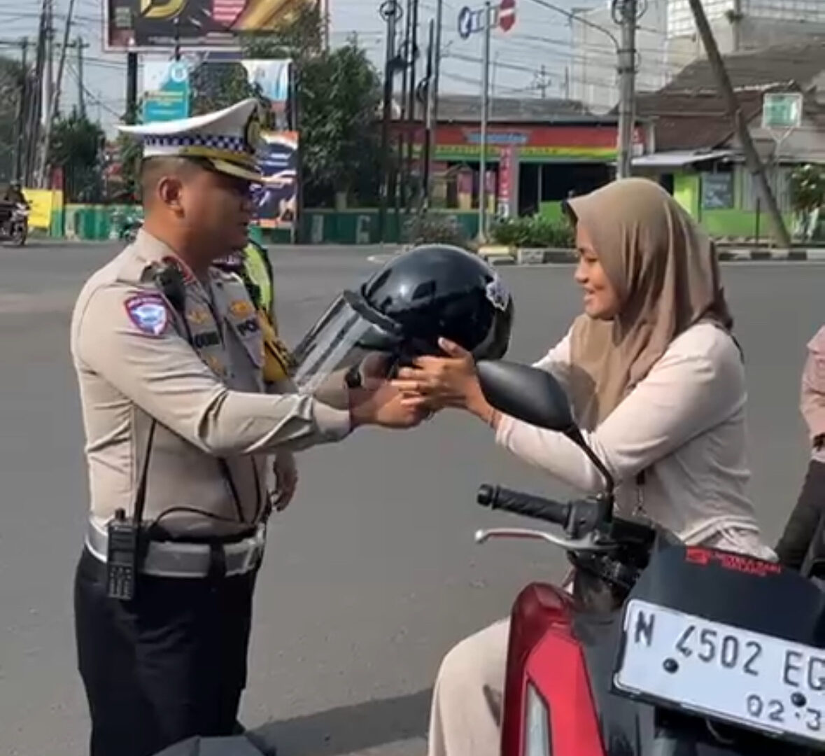 Petugas Satlantas Malang Kota Membagikan Helm Gratis Kepada Pengendara Motor Dalam Operasi Zebra Semeru 2025.